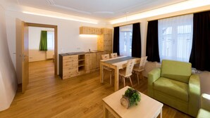 A modern living room with a dining area, wooden flooring, a green sofa, and a kitchen with wooden cabinets. - Heavenly vacation - living in the vicarage (Sölk)