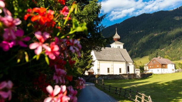 A white church with a dome, surrounded by greenery and a mountain backdrop. - Heavenly vacation - living in the vicarage (Sölk)