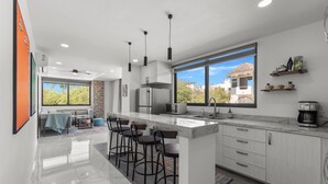 A modern kitchen with a large island, bar stools, and a view of the outdoors. - Affordable Bucerias 2 Bed. Well Stocked. Walk to Beach. Perfect Pool and Views (Bucerías)