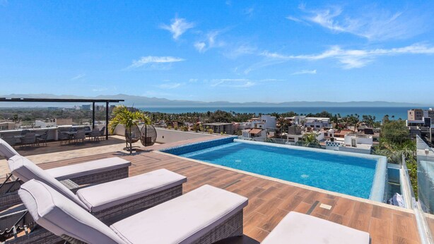 A rooftop pool with lounge chairs and a view of the sea and mountains. - Affordable Bucerias 2 Bed. Well Stocked. Walk to Beach. Perfect Pool and Views (Bucerías)