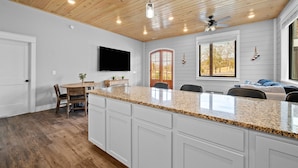 Eine geräumige Küche mit einer Granit-Arbeitsplatte, Holzboden und einem Essbereich mit Tisch und Stühlen.