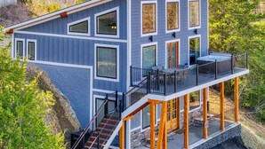 Ein modernes, zweistöckiges Haus mit Balkon, Treppe und Blick auf die umliegende Landschaft.