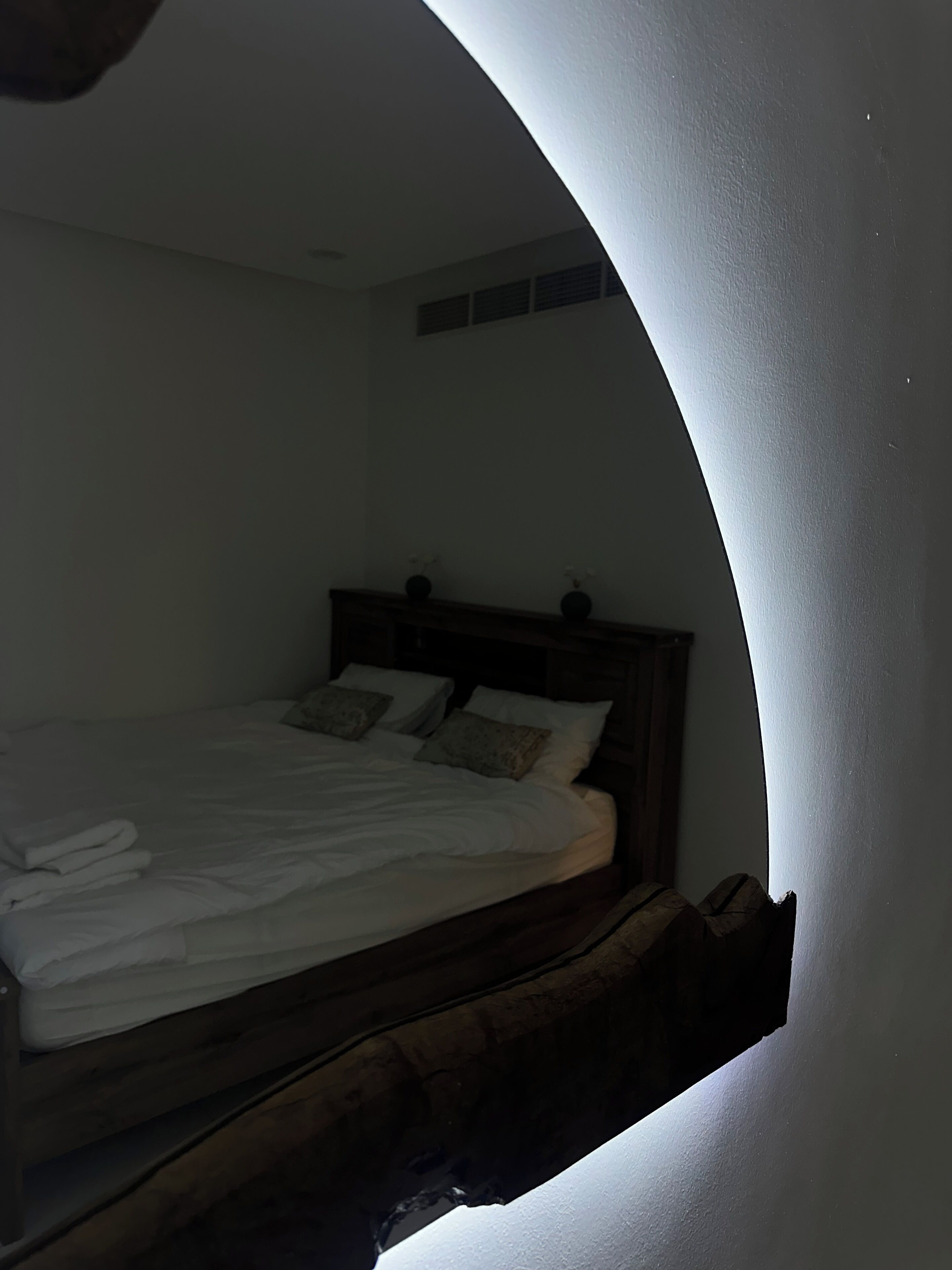 Une chambre à coucher avec un plafond incurvé, un cadre de lit en bois et un matelas blanc.