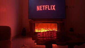 Una sala de estar con una televisión mostrando 'NETFLIX' y una chimenea.
