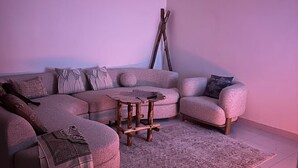 Una sala de estar con un sofá seccional, una mesita redonda y una alfombra.