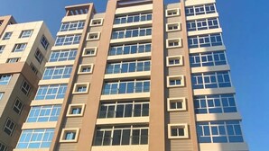 Un edificio de varios pisos con un diseño arquitectónico moderno, que cuenta con una serie de balcones y ventanas amplias.