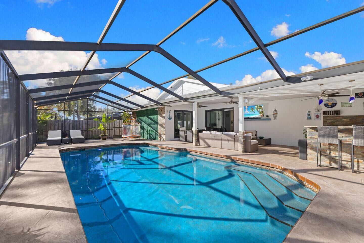 Une piscine dotée d’un toit en verre, de chaises longues et d’un espace bar.