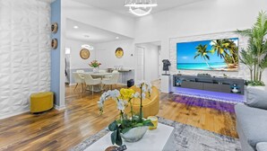 Een moderne woonkamer met een televisie, een eethoek en een keuken.