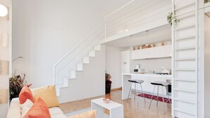 Un salon moderne avec un escalier menant à une cuisine.