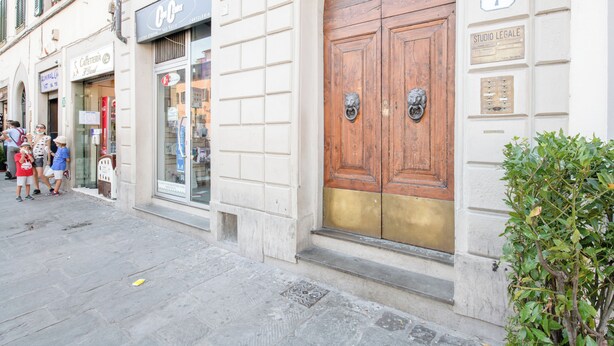 Une rue avec une grande porte en bois, un café et un magasin avec une enseigne.
