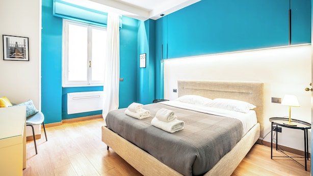 Une chambre d’hôtel moderne avec un grand lit, une table de chevet avec une lampe et une vue sur l’extérieur.