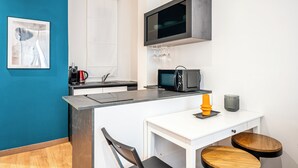 Une cuisine compacte équipée d’un four à micro-ondes, d’une machine à café et d’un petit coin repas avec des tabourets.