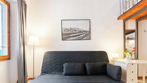 Una habitación moderna con un sofá gris, un escritorio y una fotografía en blanco y negro enmarcada en la pared.