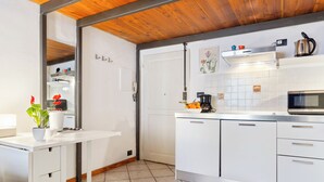 Una cocina moderna con armarios blancos, microondas, cafetera y una planta en maceta.