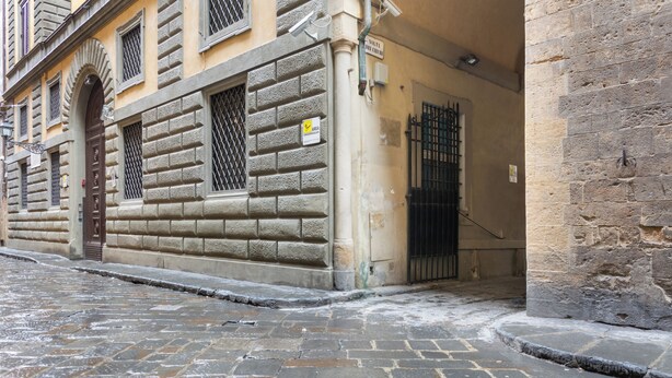 Un edificio histórico con fachada de piedra, una entrada arqueada grande y un acceso con portón.