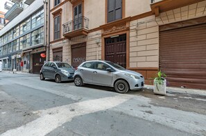 A street with parked cars and a building with a closed shutter. - Guesthost - Teatro Massimo Roomy Flat With Covered Terrace (Palermo)