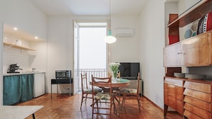 A compact kitchen with a dining table, chairs, a microwave, and a TV. - Guesthost - Teatro Massimo Lovely Flat With Balconies (Palermo)