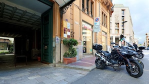 A building with a green entrance, a sign prohibiting parking, and a motorcycle parked on the street. - Guesthost - Teatro Massimo Lovely Flat With Balconies (Palermo)