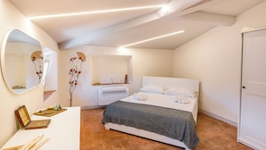 Una camera da letto con un letto, un comodino, uno specchio e un condizionatore d'aria a parete.