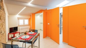 Zona pranzo con tavolo in vetro, sedie e televisione su un mobile.