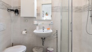Een moderne badkamer met toilet, wastafel en douche.
