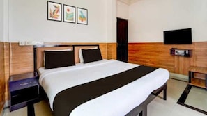 A hotel room with a large bed, wooden headboard, a flat-screen TV mounted on the wall, and artwork above the bed. - Hotel O Gummidipundi Railway Junction (Gummidipundi)