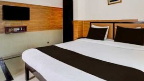 Une chambre d’hôtel avec un lit, un téléviseur fixé au mur et un petit cadre photo.