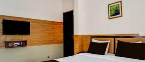 Una habitación de hotel con una cama, un televisor montado en la pared y un pequeño marco de fotos.