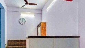 Une pièce avec un ventilateur de plafond, une horloge au mur, un canapé et un meuble.