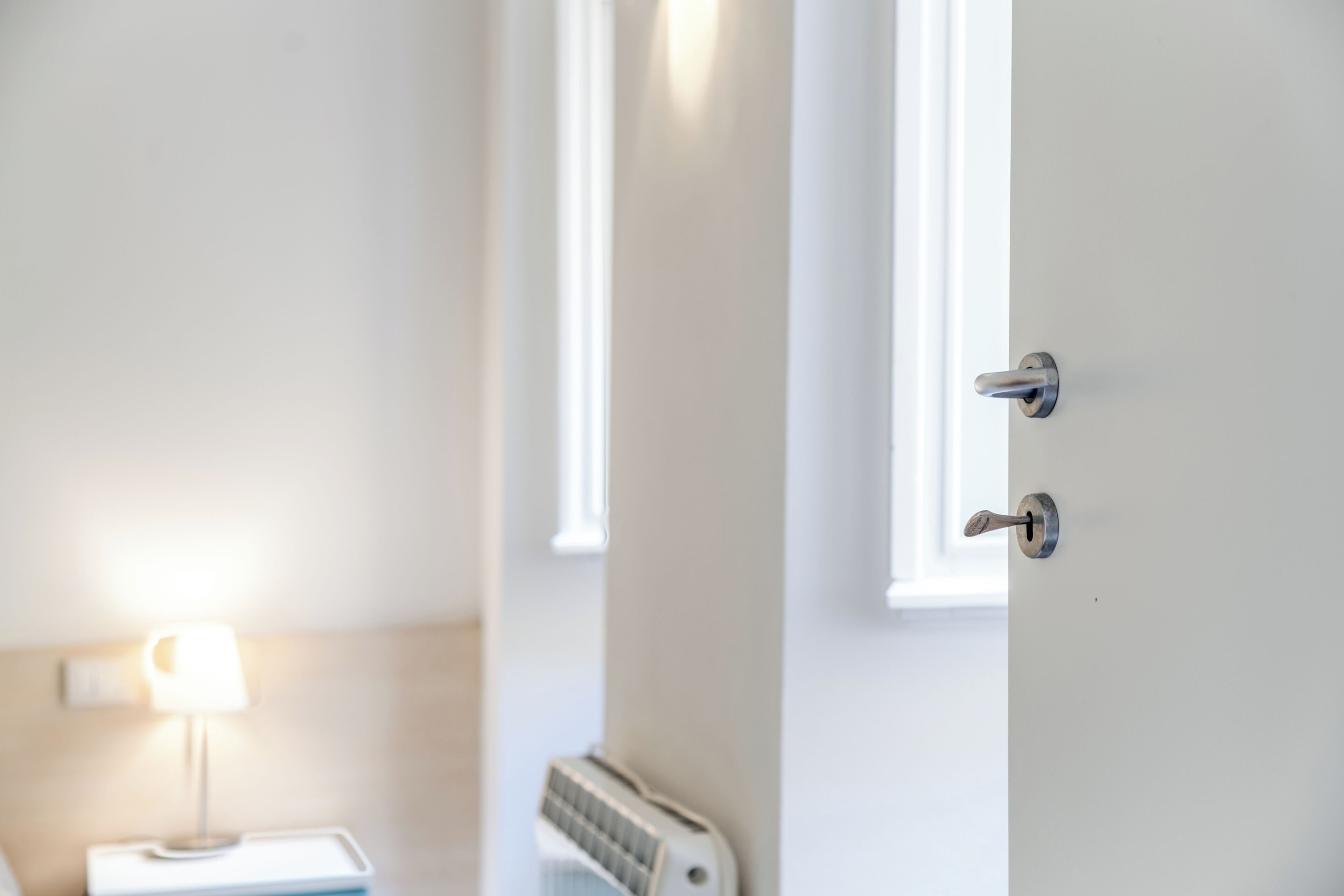 A room with a bed, a nightstand with a lamp, and a radiator.