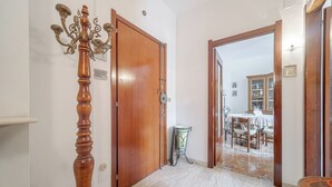 A hallway with a wooden door, a candelabra, and a dining area in the background. - Guesthost - New! Rapallo Bellavista Vintage Flat X4 (Rapallo)