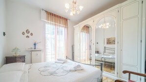 A bedroom with a large bed, a nightstand, a dresser, a mirror, and a bench. - Guesthost - New! Rapallo Bellavista Vintage Flat X4 (Rapallo)