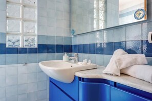 Ein Badezimmer mit Waschbecken, blauen Fliesen und einem Handtuch.