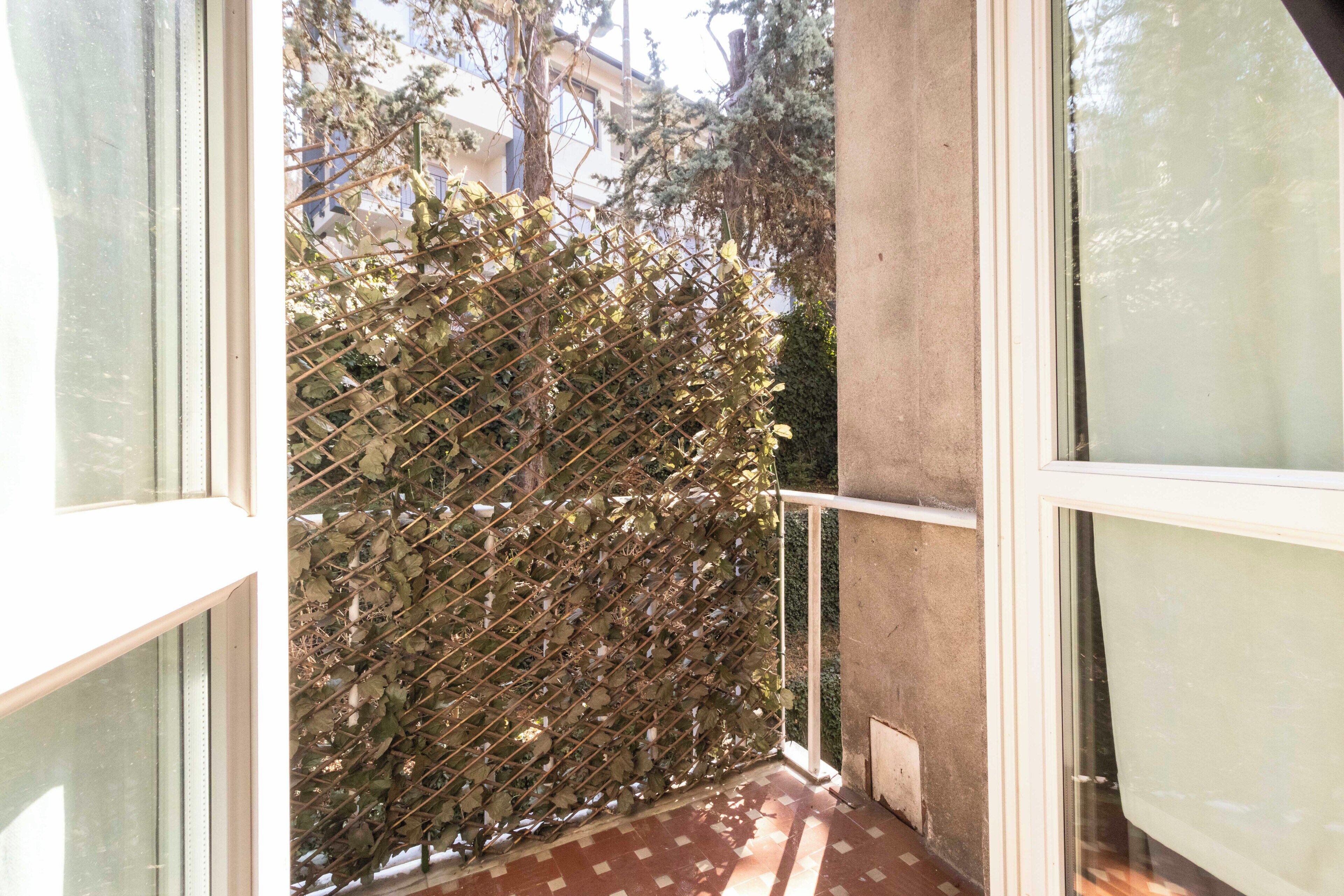 A balcony with a metal trellis and a view of buildings.