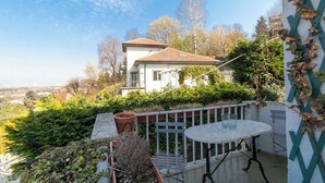 Ein Balkon mit Tisch und Stühlen, einem Blumentopf und Blick auf ein Haus mit Ziegeldach.