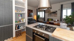 Eine moderne Küche mit Gaskochfeld, Weinkühler und Essbereich inklusive Tisch und Stühlen.