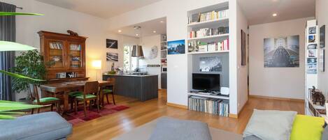 A modern living room with a dining area, kitchen, and entertainment center.