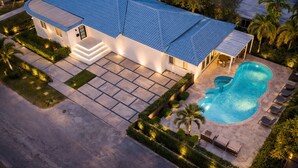 Ein modernes Haus mit Swimmingpool, einer überdachten Terrasse und einem gepflegten Garten.