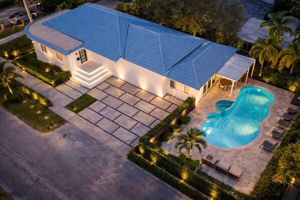 A modern house with a swimming pool, a covered patio, and a well-maintained garden. - The Rose By Brickell (Miami)