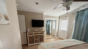 Une chambre à coucher avec un lit, une commode, un téléviseur et un ventilateur de plafond.
