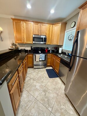 A kitchen with wooden cabinets, a stainless steel refrigerator, a microwave, and a stove.
