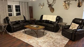 A living room with a sectional sofa, a coffee table, a fireplace, and mounted animal heads on the wall.