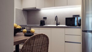 Una cocina moderna con un refrigerador de acero inoxidable, un microondas y un lavamanos.