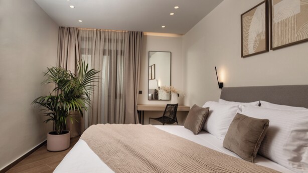 Una habitación de hotel moderna con una cama grande, un escritorio, una silla y una planta en maceta.