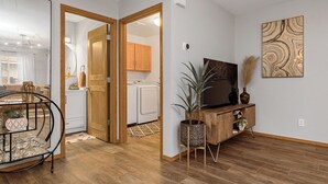 Ett modernt kök med träskåp, en tvättmaskin och en matplats med en stol och ett bord i metall.