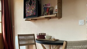 Une pièce comprenant une chaise en bois, une table, une étagère remplie de livres et une fenêtre avec des rideaux.