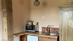 Une cuisine compacte équipée d’un four à micro-ondes encastré, d’un petit réfrigérateur et d’un évier.