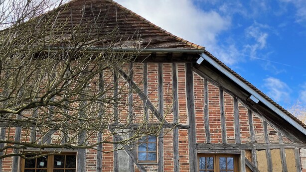 Il s’agit d’un bâtiment traditionnel à colombages, doté d’un toit à forte pente, de grandes portes en bois et d’une petite fenêtre.