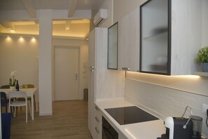 Una cocina moderna con estufa integrada, armarios blancos y un comedor con mesa y sillas.