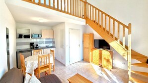 Amplia sala de estar con escalera de madera, cocina equipada con electrodomésticos modernos y comedor con mesa y sillas.